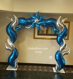 a blue and silver balloon arch in the shape of a dragon