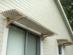 an outside view of a house with two windows and a wooden awning over the door