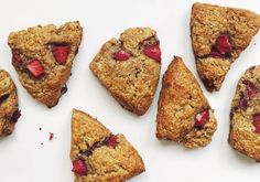 several pieces of fruit and oatmeal scones arranged on a white surface