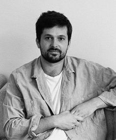 black and white photo of man sitting on couch with arms crossed, looking at camera