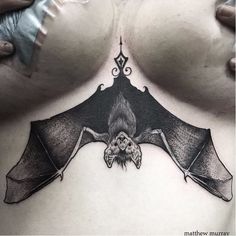 a woman's chest with a bat tattoo on it