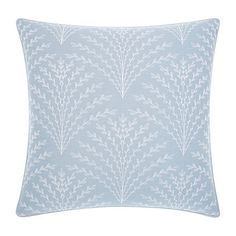 a light blue pillow with white leaves on the front and back, sitting on a white background