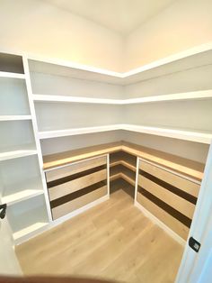 an empty room with white shelving and wood flooring in the corner is shown