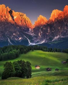 the mountains are covered in snow and green grass, with small houses on each side