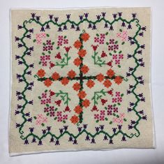 a cross - stitch pattern with flowers and leaves on white fabric, which is very decorative