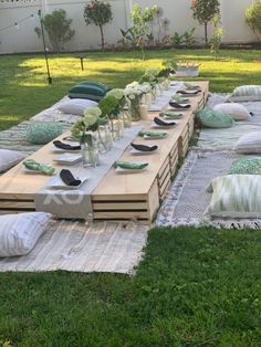 a long table set up in the middle of a yard with lots of pillows on it