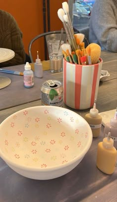 an empty bowl sitting on top of a wooden table next to bottles and other items