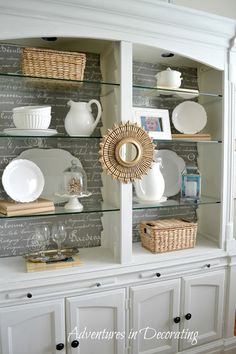 a white china cabinet with glass shelves filled with dishes