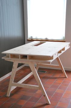 a wooden table sitting on top of a red tile floor next to a white window