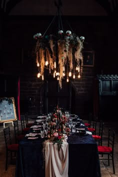 the table is set up for an event with black linens and red velvet chairs