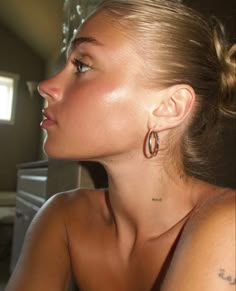 a woman with large hoop earrings on her ear looking off to the side in a room