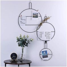 two metal circles with pictures hanging from them on a wall next to a table and vase