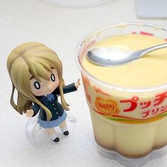 a plastic doll next to a cup of yogurt