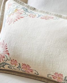 a close up of a pillow on a bed with white linens and pink flowers