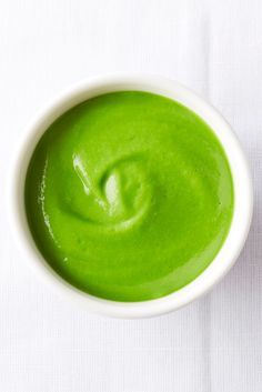 a white bowl filled with green liquid on top of a white cloth covered tablecloth