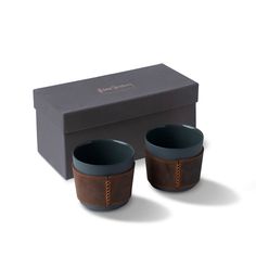 two brown cups sitting in front of a black box