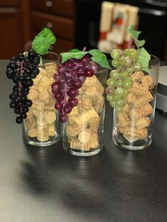 three glasses filled with wine corks and grapes