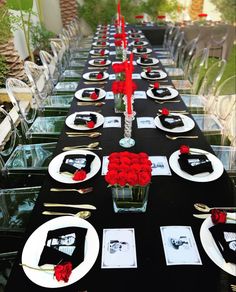 the table is set with black and white plates, red roses, and silverware