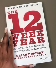 a person holding up a book with the title 12 week new year written on it