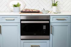 a stove top oven sitting inside of a kitchen next to a counter with potted plants