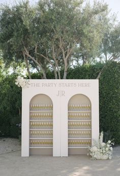 the entrance to the party starts here sign is decorated with white flowers and gold vases