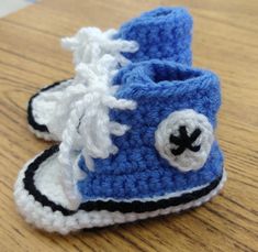 a crocheted blue and white baby boot on a wooden table