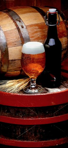 two glasses of beer sitting on top of barrels