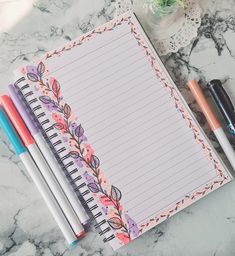 notebooks and pens sitting on top of a marble table next to an empty notepad