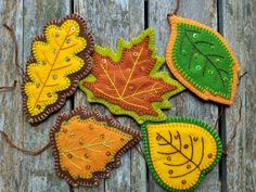 four autumn leaf ornaments on a wooden surface