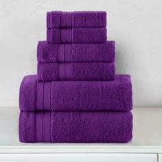 a stack of purple towels sitting on top of a white dresser