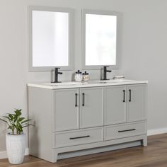 a bathroom vanity with two mirrors above it and a potted plant on the floor