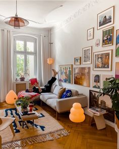 a living room filled with furniture and lots of pictures on the wall next to a window