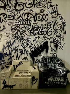 graffiti is on the wall next to two couches and boxes in front of it