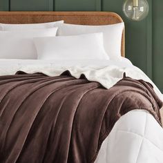 a bed with white sheets and brown blanket