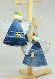 two angel ornaments hanging from clothes pegs on a wooden stand in front of a white background