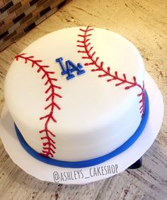 a white cake with red and blue stitches on it that is decorated like a baseball