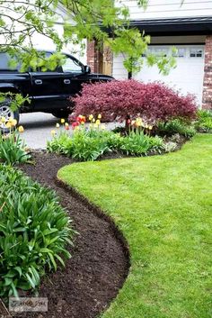 a truck parked in front of a house next to a lush green lawn and flower bed