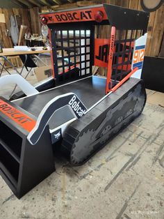 a large snow plow sitting on top of a wooden floor