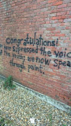 graffiti on the side of a brick building reads congratulations, you have impressed the voice of the young men now speak through paint