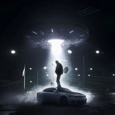 a man standing on top of a car in front of a large alien like object