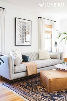 a living room filled with furniture and a large rug on top of a hard wood floor