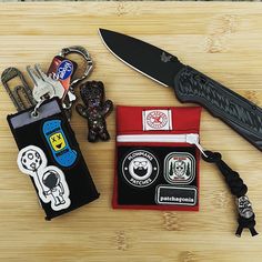 a knife, wallet and keychain sitting on top of a wooden table next to each other