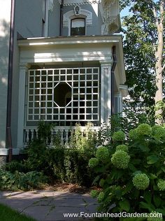 a white house with an arched window and garden in front