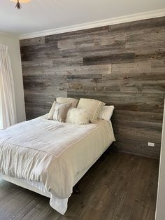 a large bed sitting in the middle of a bedroom next to a wooden headboard