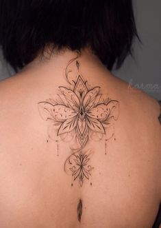 the back of a woman's neck with a flower tattoo on it