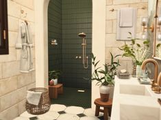 a bathroom with green tiled walls and flooring, along with two sinks and a walk in shower