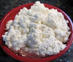 a red bowl filled with cottage cheese on top of a table