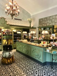 the interior of a store with green cabinets and chandelier hanging from the ceiling