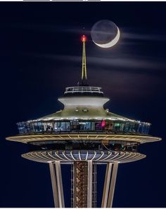 the moon is setting over the space needle in seattle, wa at night as seen from below