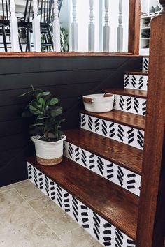 the stairs are decorated with black and white geometric tiles, potted plants on each step